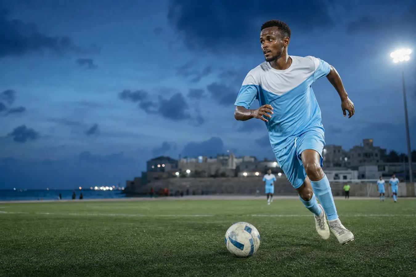 Somali footballers in a match, one player striking the ball on a sandy pitch as team mates close in